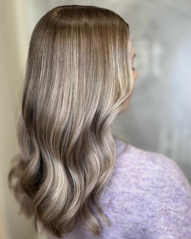 Красивые волнистые волосы цвета капучино коричневого цвета со светлыми бликами.