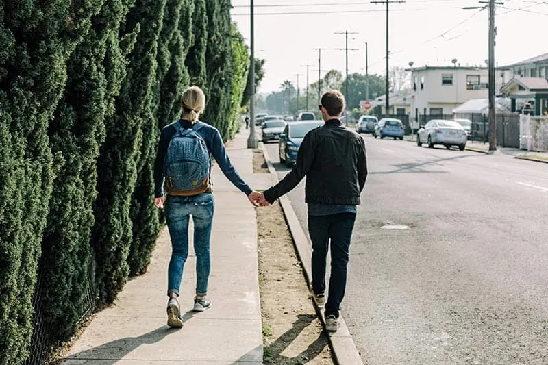 Пара в джинсах, держась за руки во время прогулки по улице