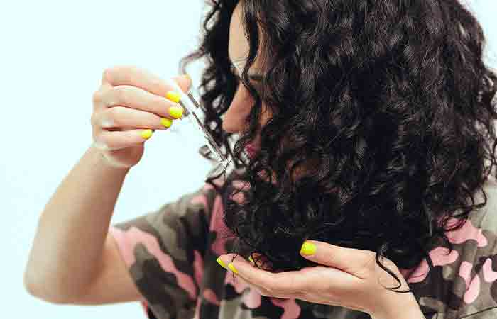 Молодая женщина наносит на волосы кокосовое масло